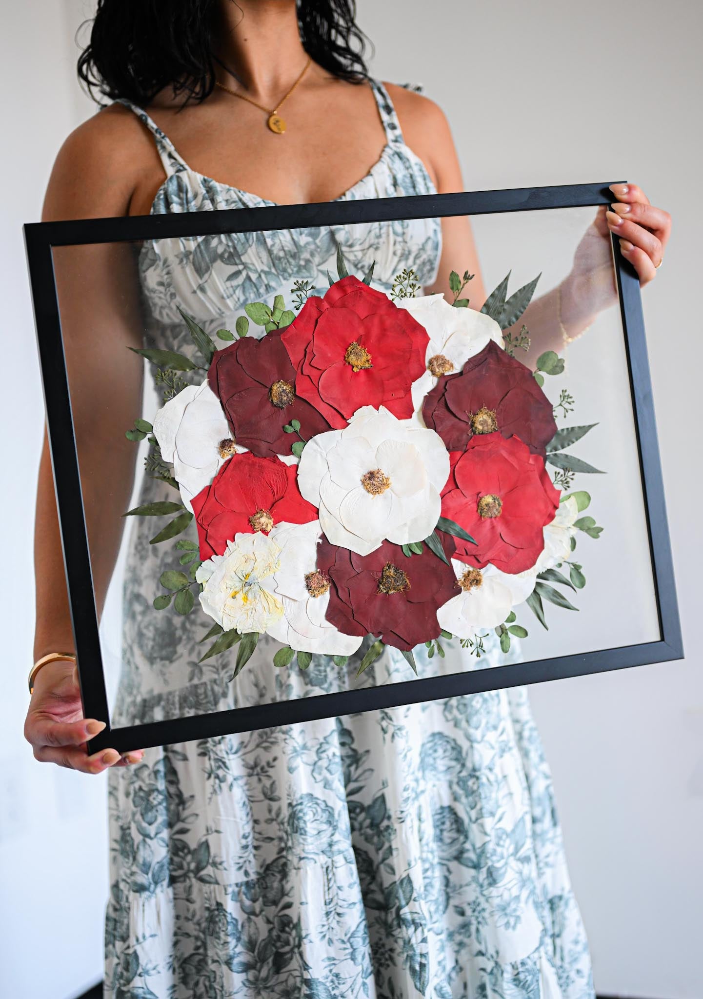 Person holding a framed of pressed flowers