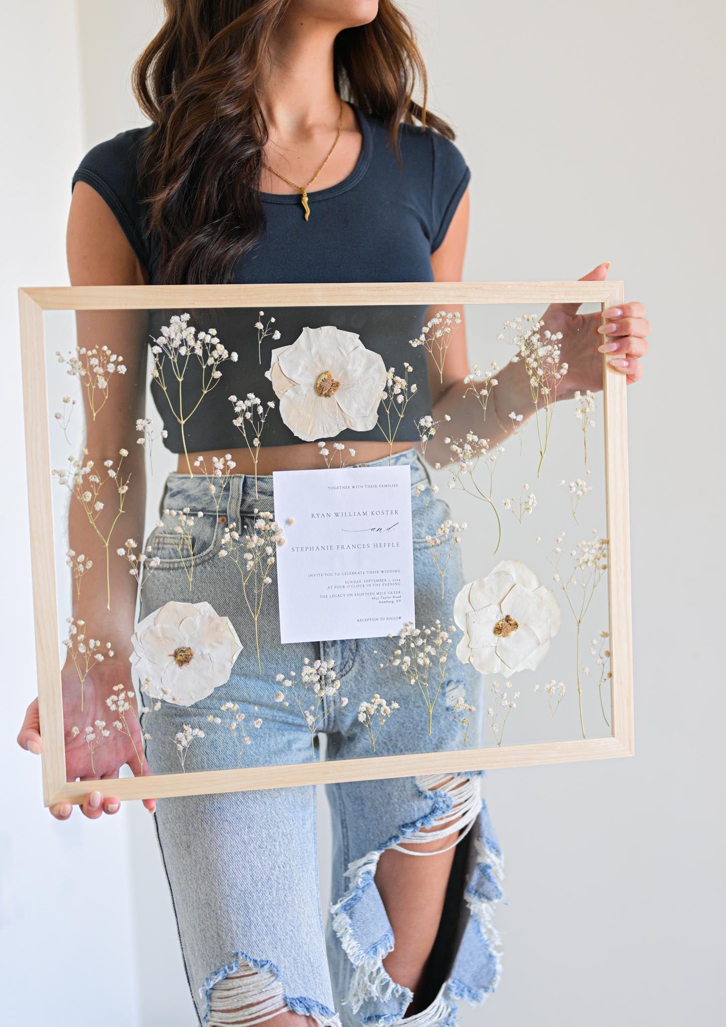 A person holding a wooden frame with preserved floral 
