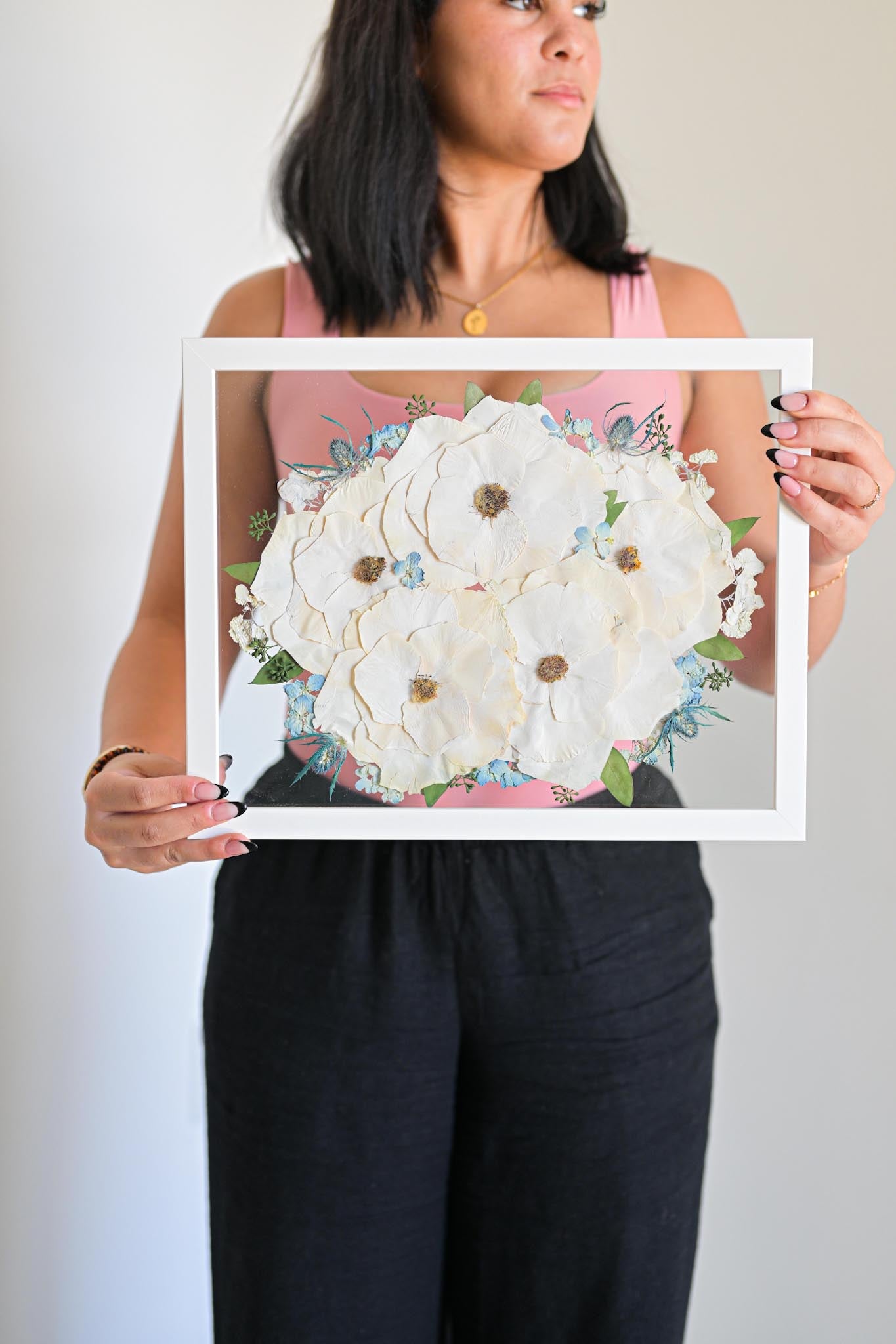 Woman holding a framed artwork of white flowers 