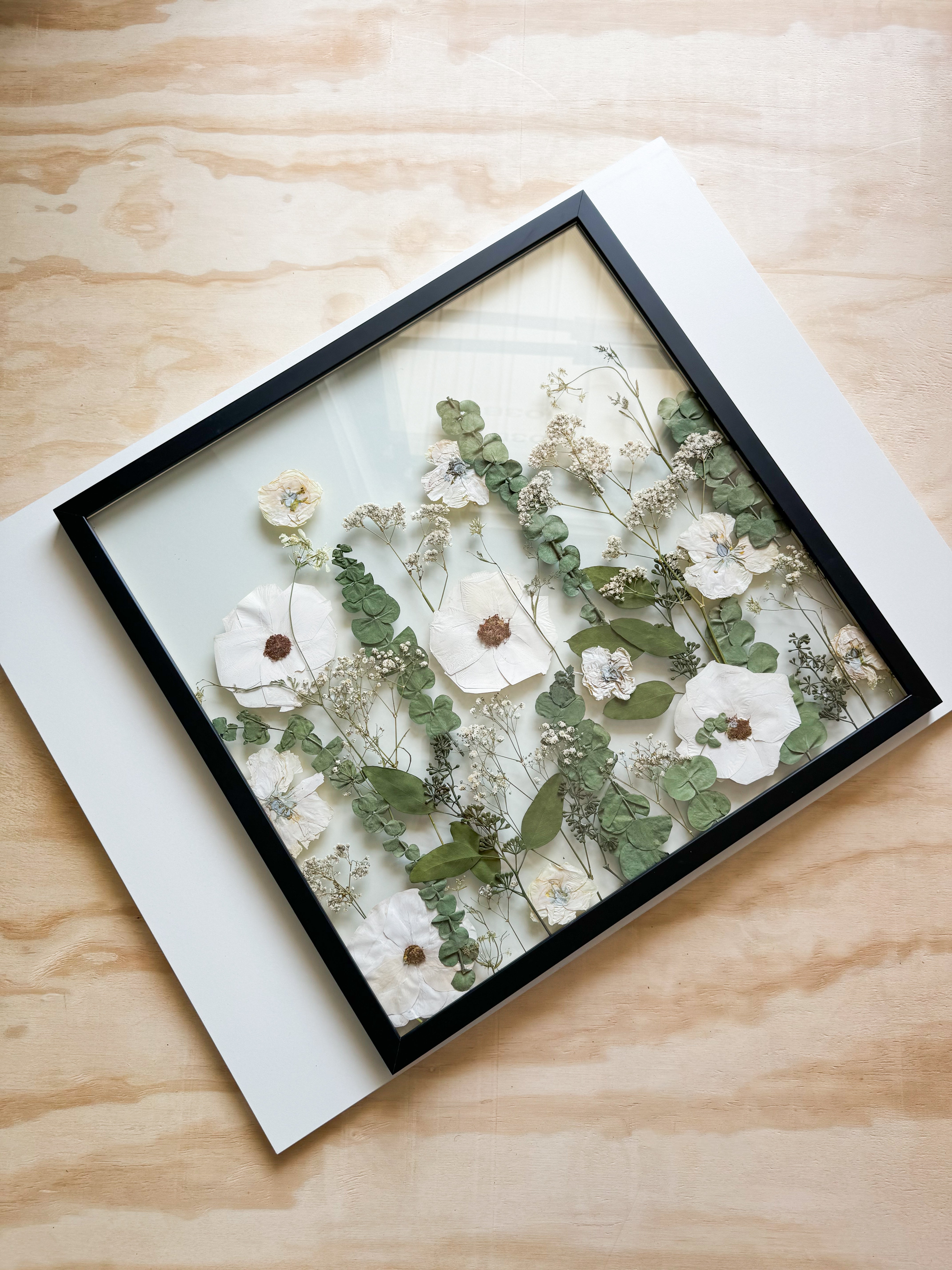 A wooden frame with a floral artwork inside
