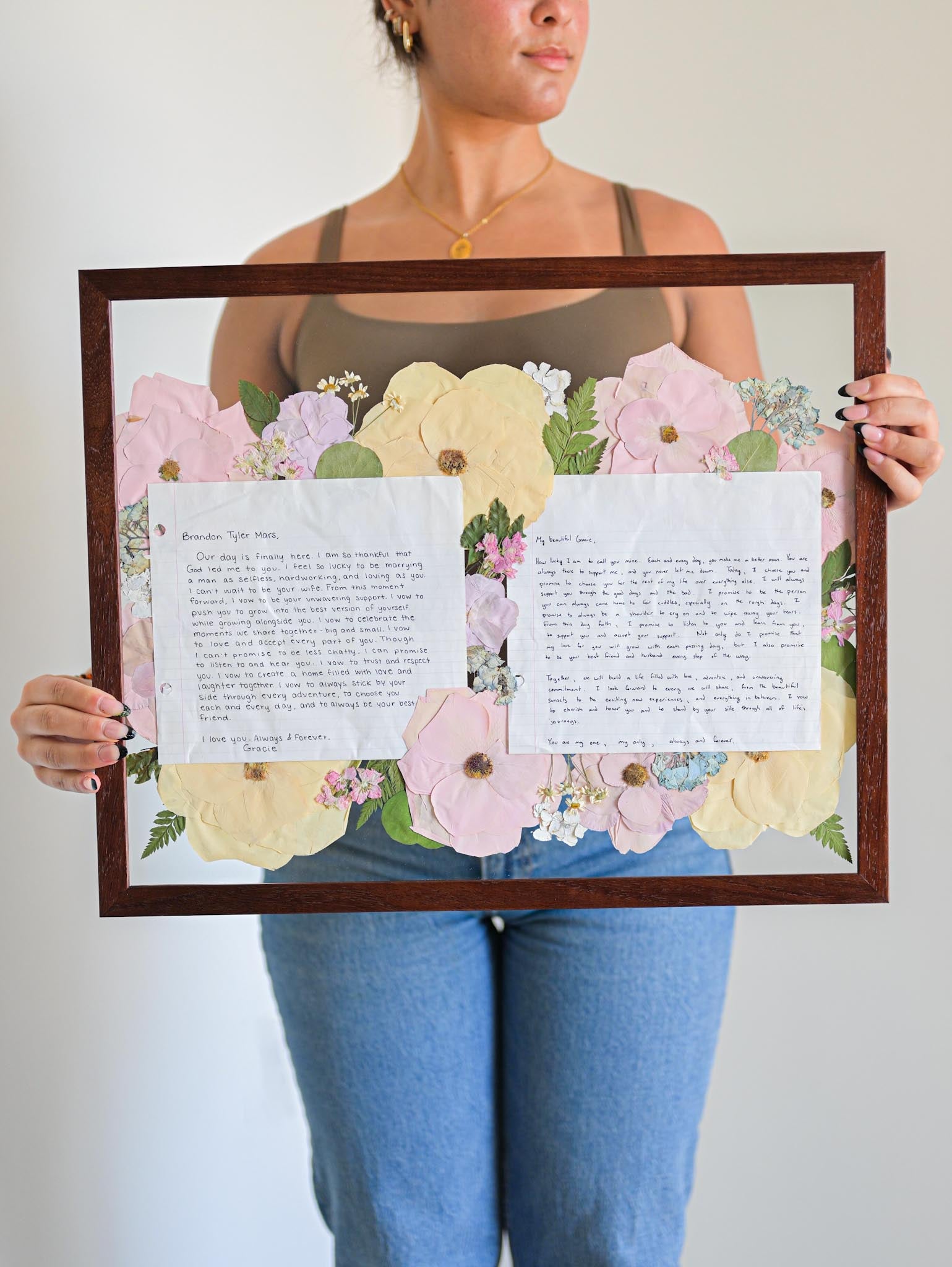 A person holding a wooden frame with preserved floral 