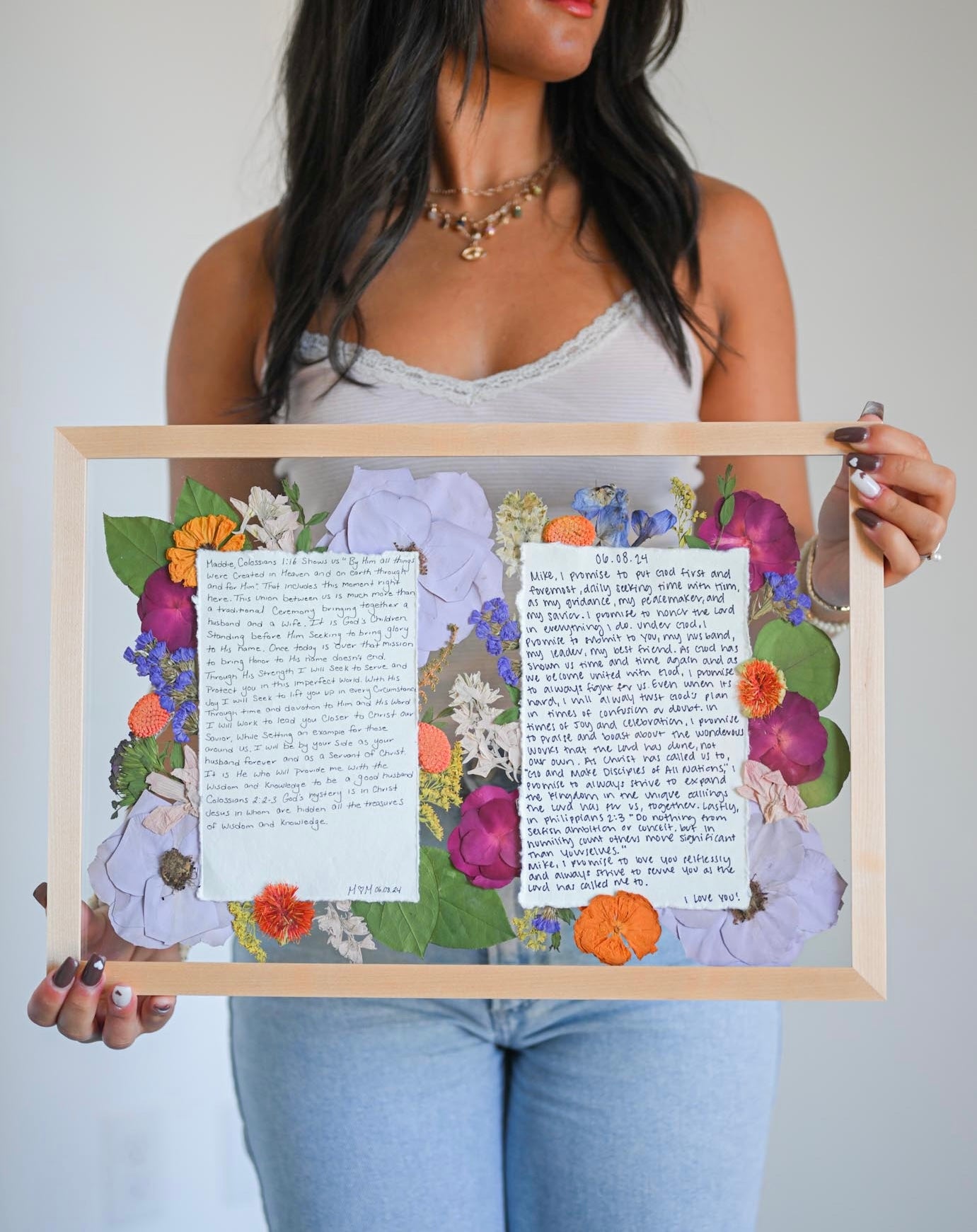 girl holding a framed artwork with floral decorations and text.