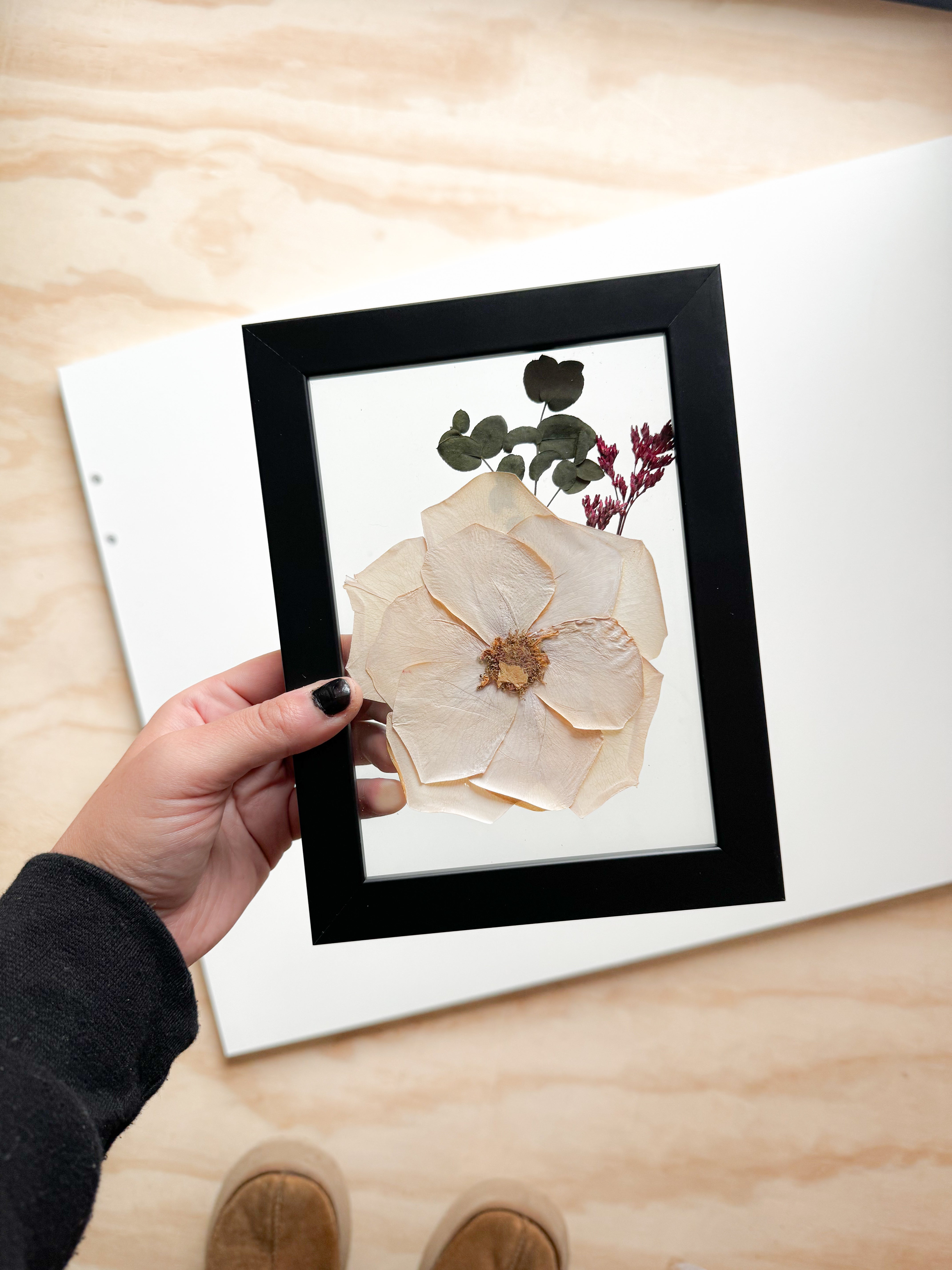 white pressed flower inside frame