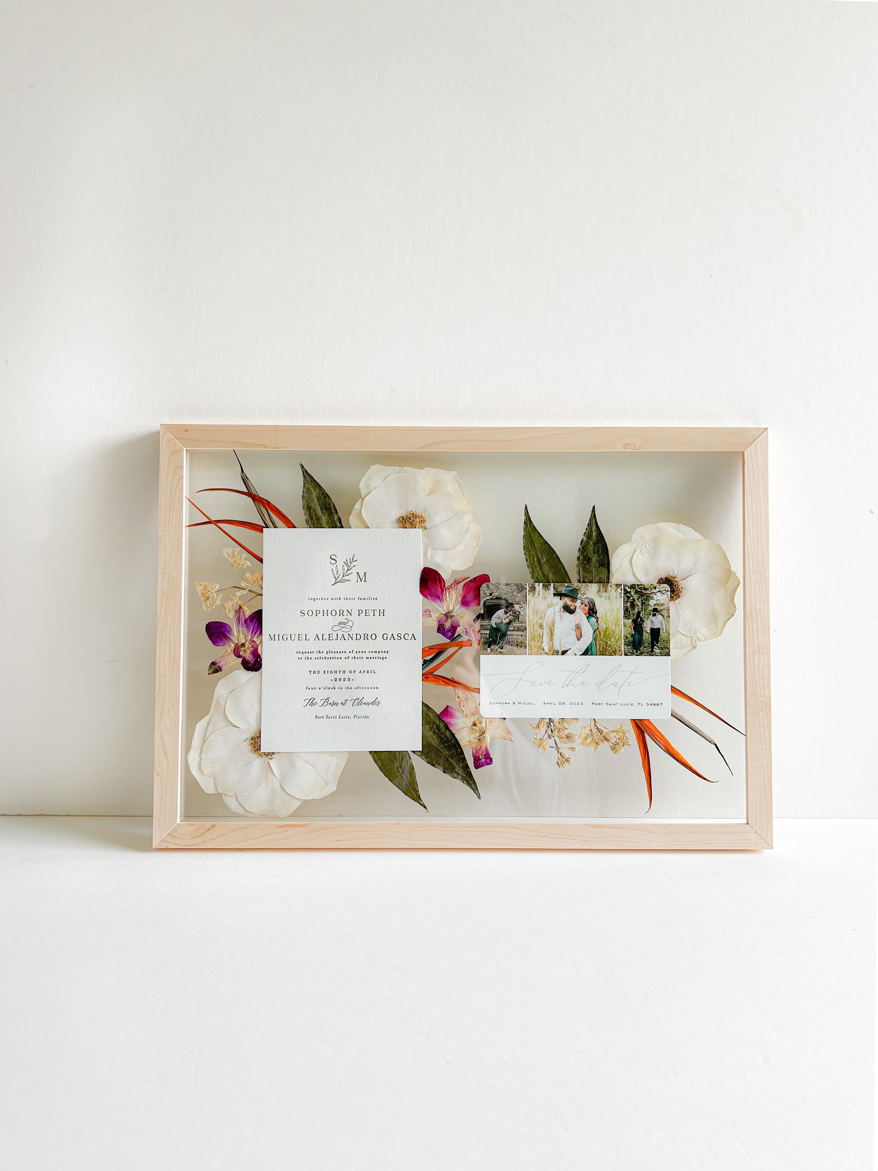 frame with a floral design and a wedding invitation inside
